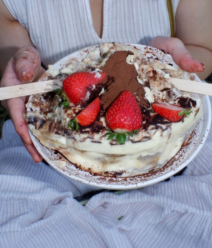 Classic tiramisu with fresh strawberries held on a plate